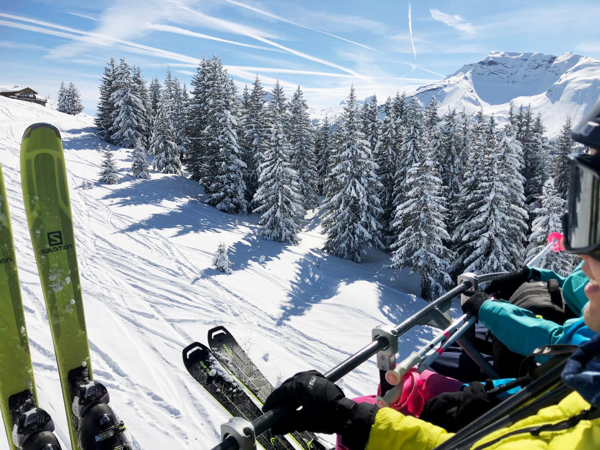 Skiiers on chairlift making way to top of ski slope